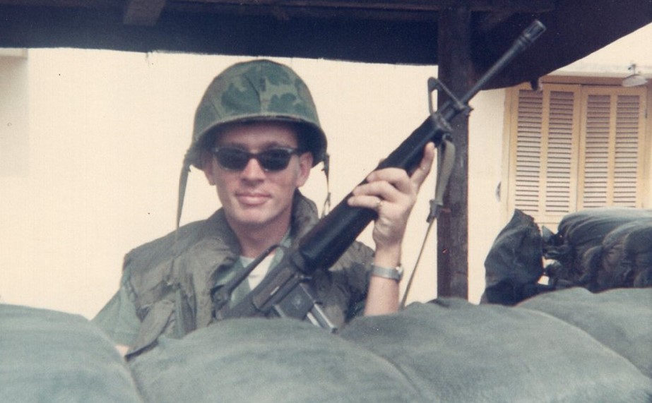 Man in military uniform with sunglasses holding a gun